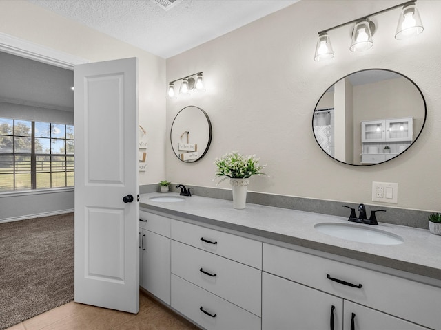 bathroom with tile patterned floors, vanity, and a textured ceiling