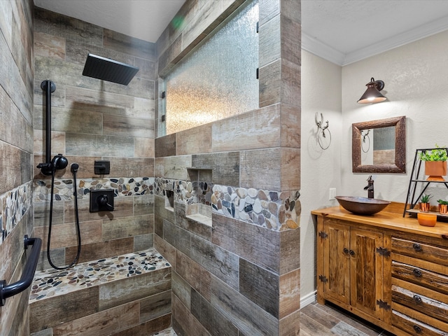 bathroom featuring tiled shower, wood-type flooring, vanity, and ornamental molding