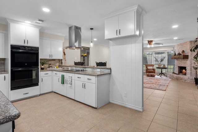 kitchen featuring ceiling fan, decorative light fixtures, island range hood, a fireplace, and black appliances