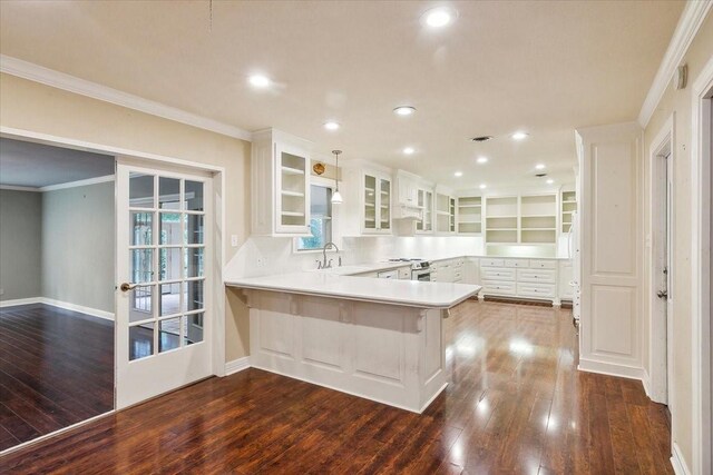 3301 Pelican St, Orange, TX 77630 - kitchen featuring dark wood-style floors, white cabinetry, crown molding, and a peninsula