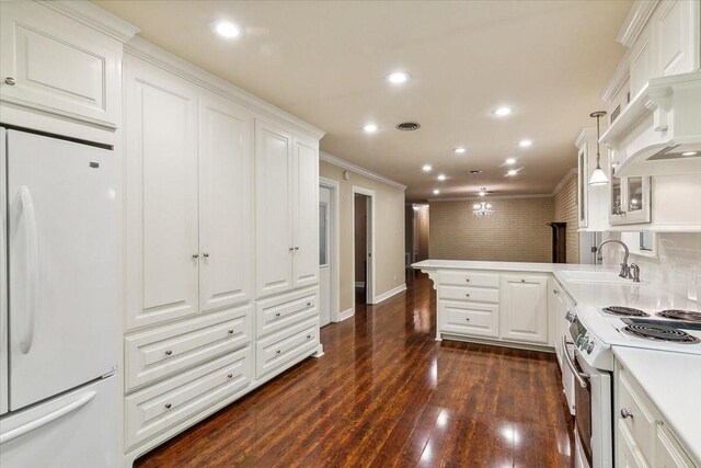 3301 Pelican St, Orange, TX 77630 - kitchen with a peninsula, white appliances, ornamental molding, white cabinetry, and a sink