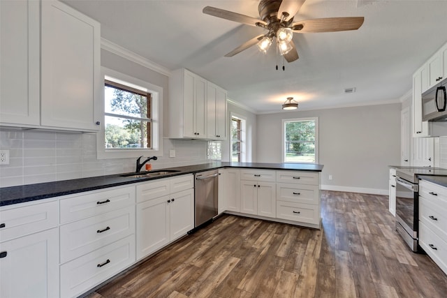 kitchen with appliances with stainless steel finishes, sink, white cabinets, decorative backsplash, and kitchen peninsula