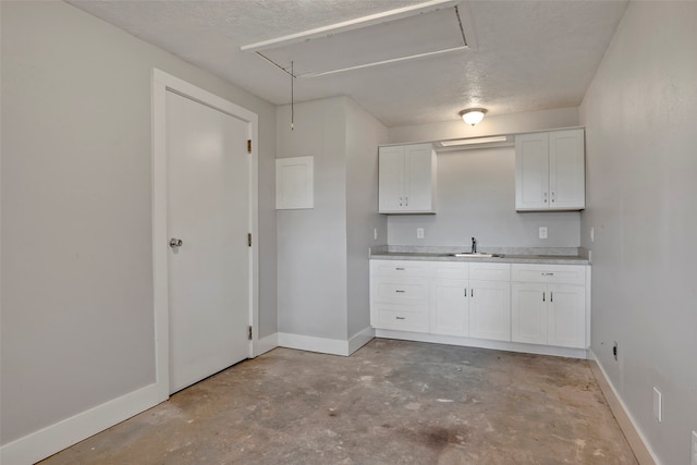 kitchen with sink, a textured ceiling, and white cabinets