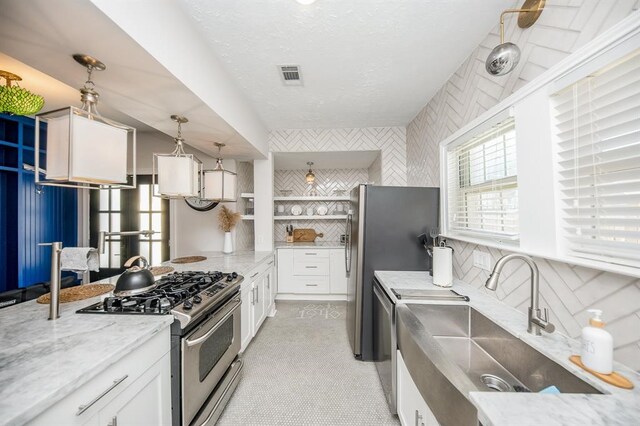 kitchen with white cabinets, stainless steel appliances, hanging light fixtures, and sink