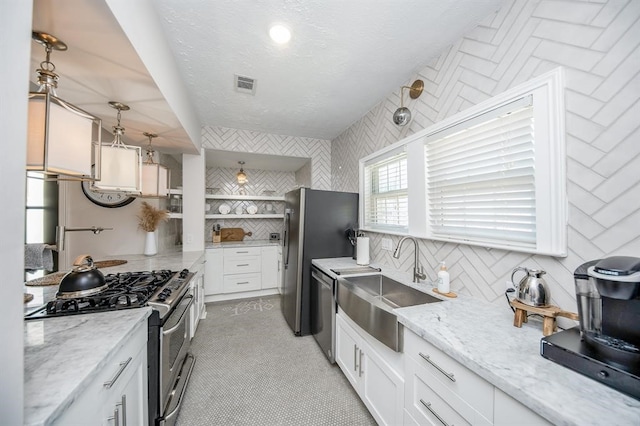 kitchen featuring sink, white cabinetry, stainless steel appliances, decorative light fixtures, and light stone counters