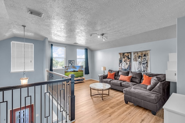 living room featuring a textured ceiling, wood-type flooring, and vaulted ceiling