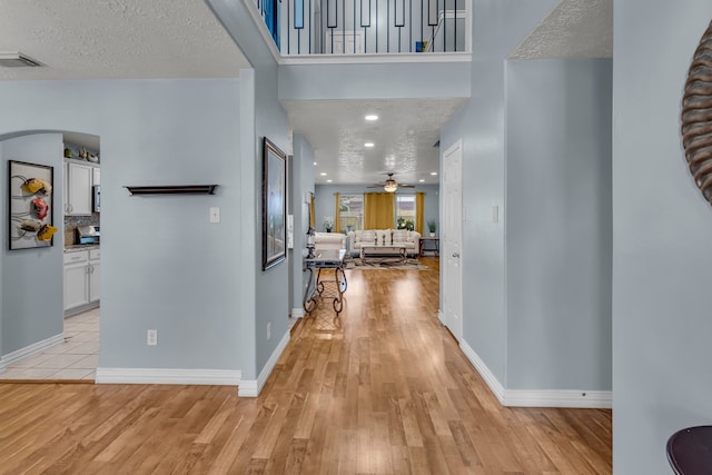 corridor with light wood-type flooring and a textured ceiling