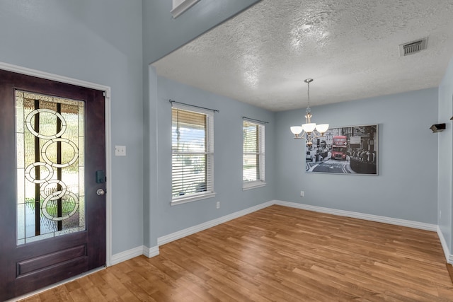 foyer featuring a notable chandelier, a textured ceiling, and hardwood / wood-style floors