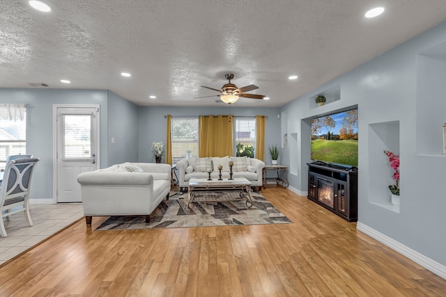 living room with light wood-type flooring, a healthy amount of sunlight, and a textured ceiling