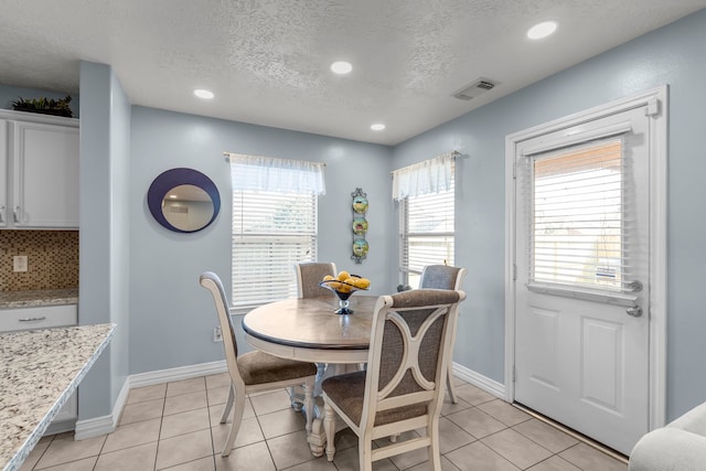 tiled dining area with a textured ceiling and a wealth of natural light