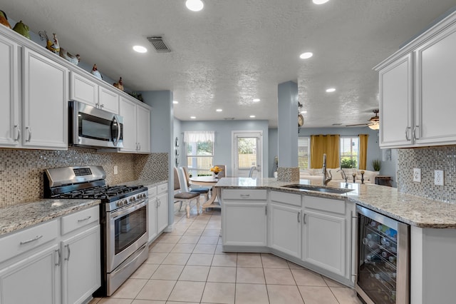 kitchen featuring white cabinets, wine cooler, sink, a textured ceiling, and stainless steel appliances