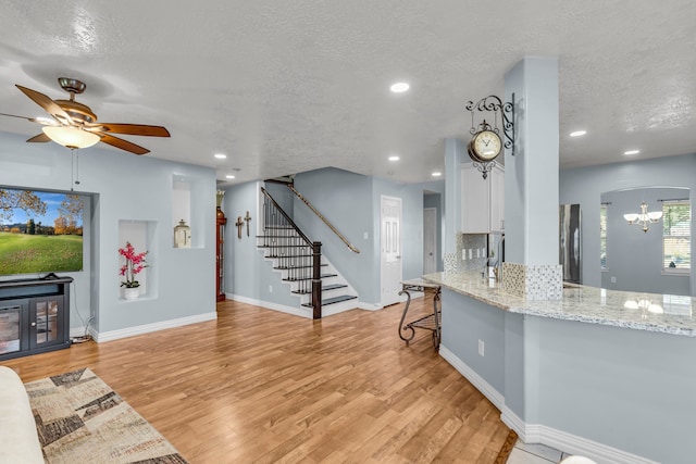 kitchen featuring light stone counters, white cabinets, a textured ceiling, and light hardwood / wood-style floors