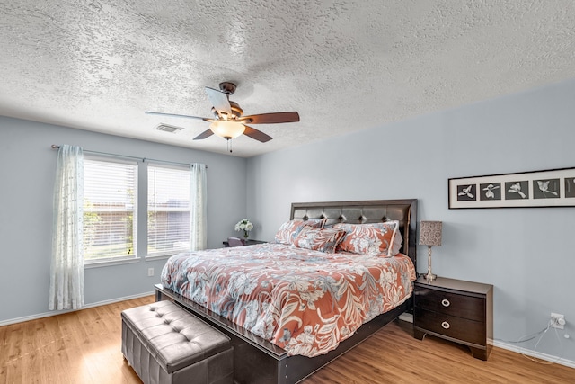 bedroom with light hardwood / wood-style flooring, ceiling fan, and a textured ceiling