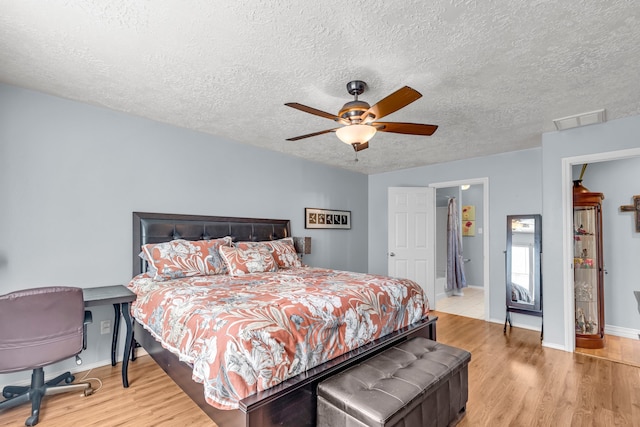 bedroom with a textured ceiling, light hardwood / wood-style floors, and ceiling fan