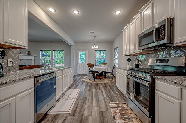 kitchen featuring decorative backsplash, white cabinets, light hardwood / wood-style floors, and appliances with stainless steel finishes