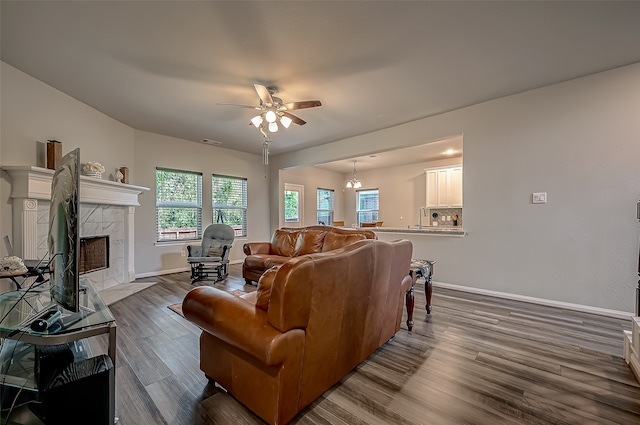 living room featuring ceiling fan with notable chandelier, a premium fireplace, and dark hardwood / wood-style flooring