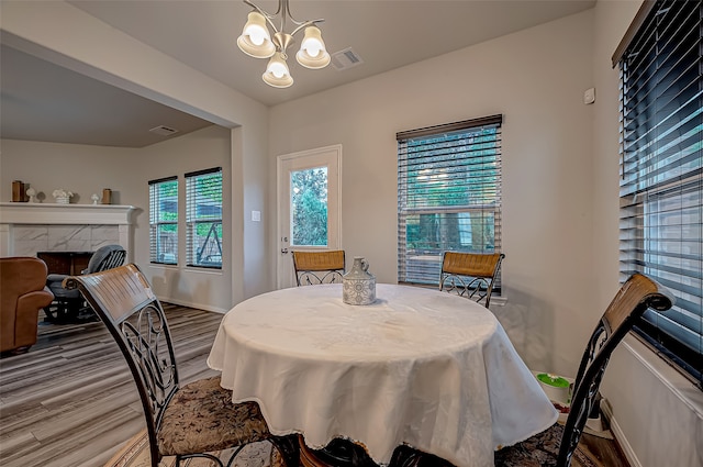 dining space with a notable chandelier, wood-type flooring, and a tiled fireplace