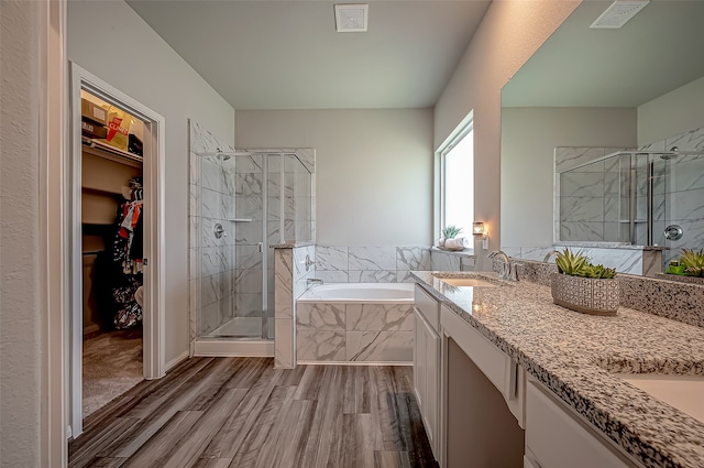 bathroom with plus walk in shower, wood-type flooring, and vanity