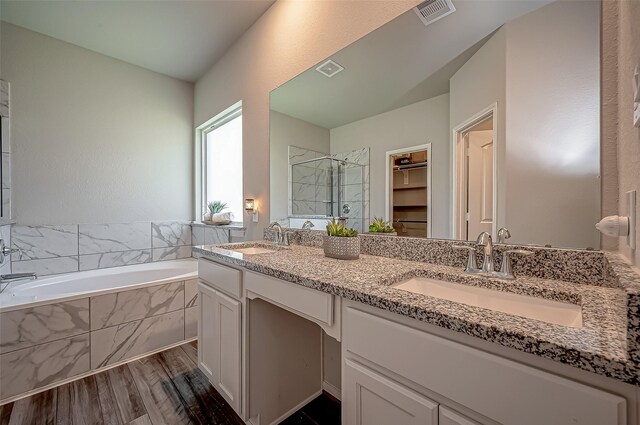 bathroom featuring plus walk in shower, wood-type flooring, and vanity