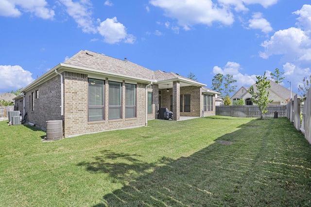 rear view of property with a lawn, a patio, a fenced backyard, central air condition unit, and brick siding