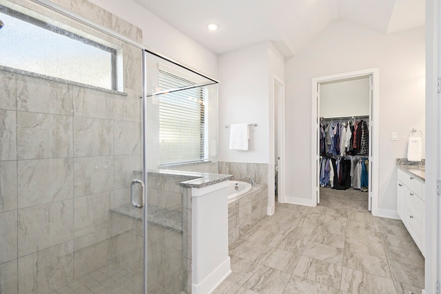 bathroom featuring independent shower and bath, vanity, and vaulted ceiling