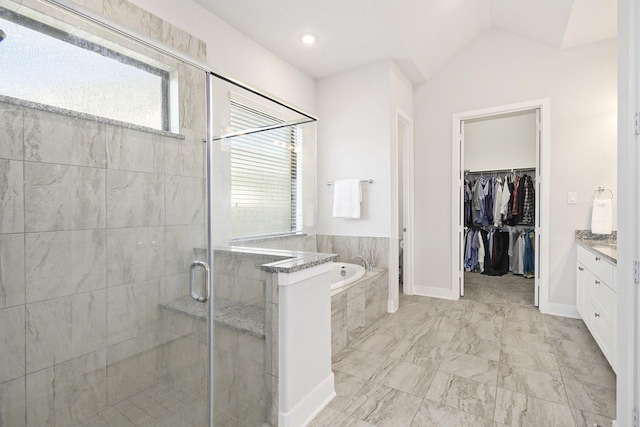 full bathroom with lofted ceiling, a garden tub, vanity, a stall shower, and a walk in closet