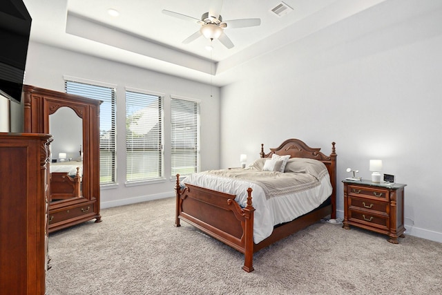 bedroom featuring light carpet, a raised ceiling, visible vents, and baseboards