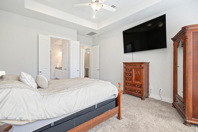 carpeted bedroom featuring connected bathroom, ceiling fan, and a raised ceiling