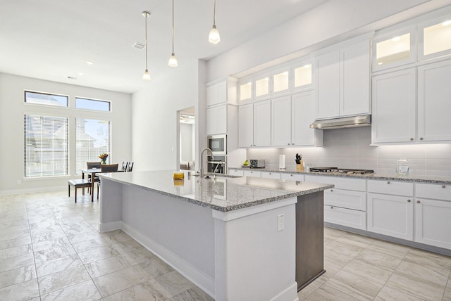 kitchen with under cabinet range hood, glass insert cabinets, and white cabinets