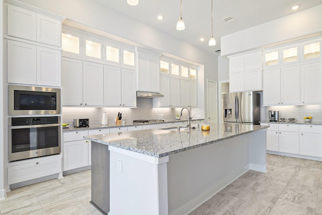 kitchen featuring a kitchen island with sink, a sink, white cabinets, appliances with stainless steel finishes, and glass insert cabinets