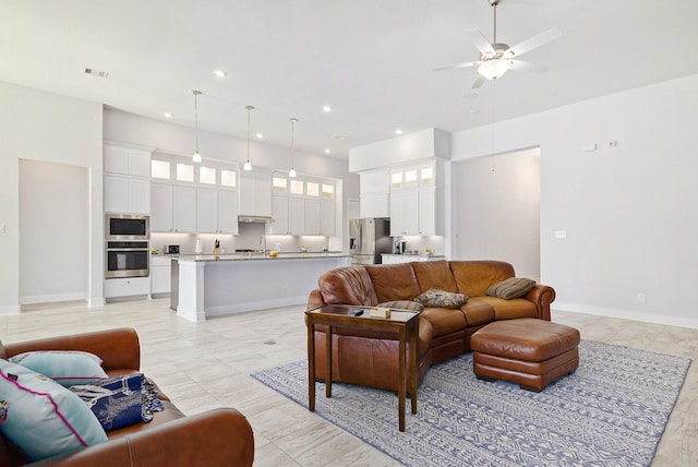 living area with recessed lighting, visible vents, a towering ceiling, a ceiling fan, and baseboards