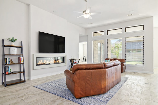 living room featuring ceiling fan and a multi sided fireplace