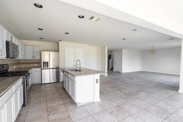 kitchen with light stone counters, sink, a kitchen island with sink, backsplash, and stainless steel appliances