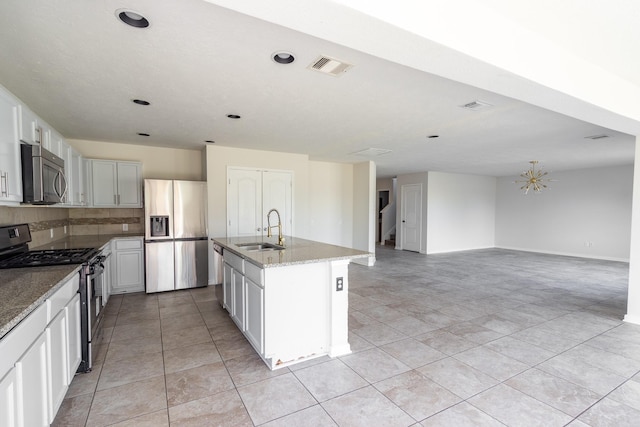 kitchen with a center island with sink, sink, light stone counters, appliances with stainless steel finishes, and decorative backsplash