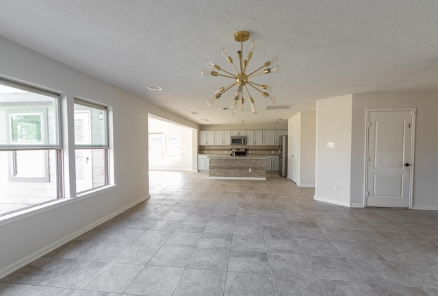 unfurnished living room featuring a textured ceiling and a notable chandelier