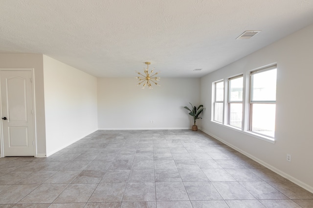 unfurnished room with a textured ceiling, light tile patterned flooring, and an inviting chandelier