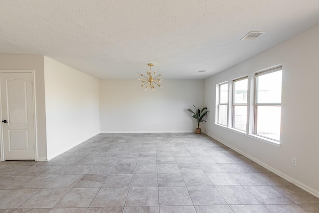 tiled empty room featuring a chandelier and a textured ceiling