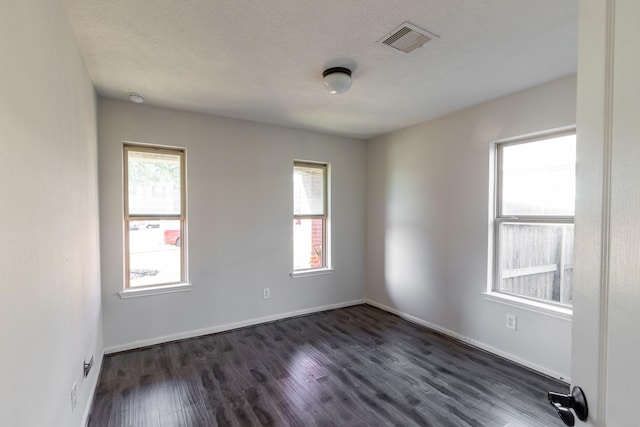 spare room featuring a textured ceiling, dark hardwood / wood-style flooring, and plenty of natural light