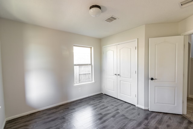 unfurnished bedroom with a textured ceiling, a closet, and dark hardwood / wood-style flooring