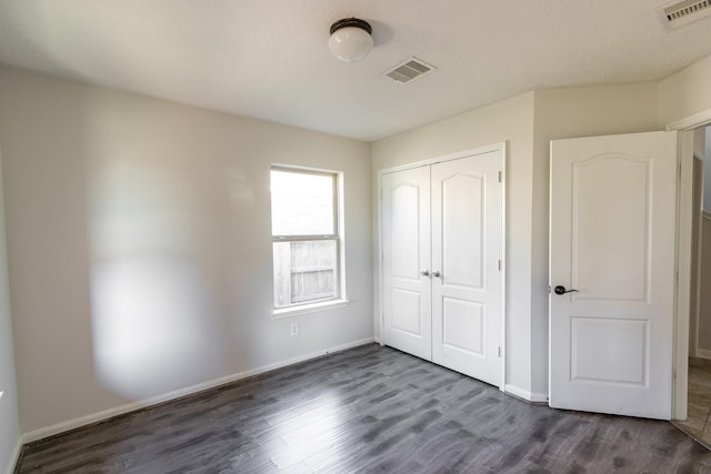 unfurnished bedroom featuring dark hardwood / wood-style flooring and a closet