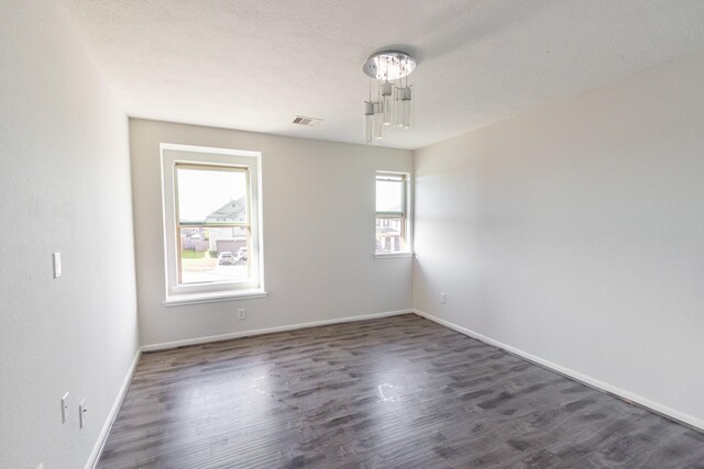 empty room featuring a textured ceiling and dark hardwood / wood-style floors