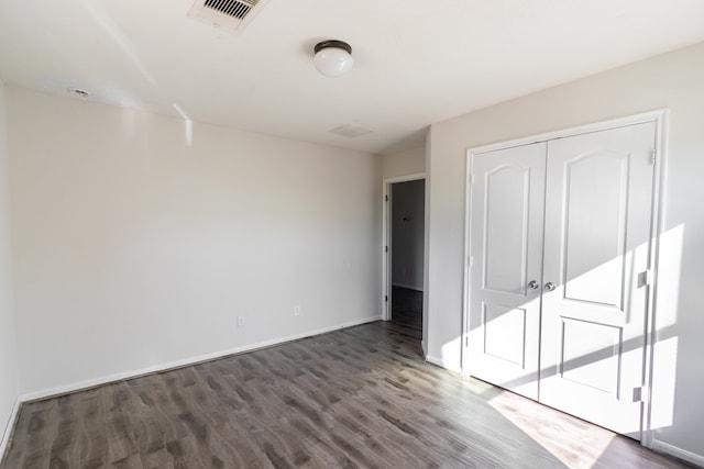 unfurnished bedroom featuring a closet and dark hardwood / wood-style floors