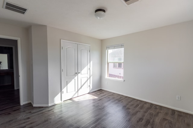 unfurnished bedroom featuring dark wood-type flooring and a closet