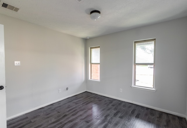 spare room featuring a textured ceiling, plenty of natural light, and dark hardwood / wood-style flooring