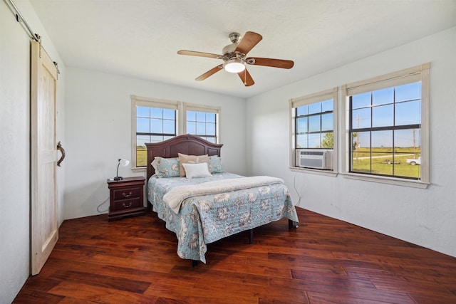 bedroom with dark wood-type flooring, cooling unit, a barn door, and ceiling fan