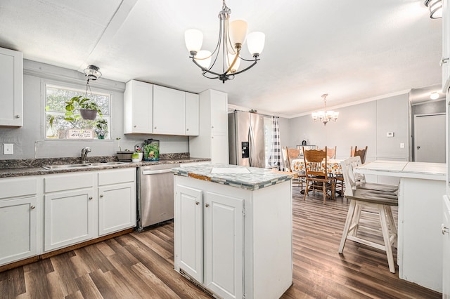 kitchen with a center island, hanging light fixtures, stainless steel appliances, an inviting chandelier, and white cabinets