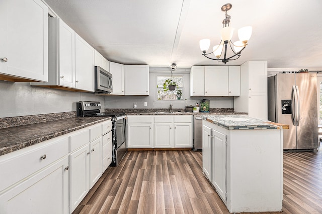 kitchen with white cabinetry, pendant lighting, stainless steel appliances, and an inviting chandelier