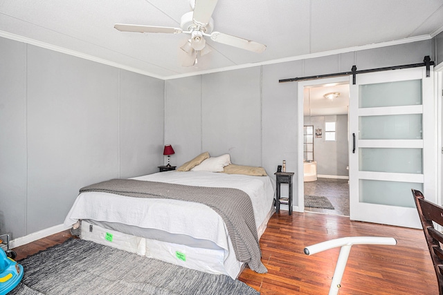 bedroom featuring hardwood / wood-style flooring, ceiling fan, a barn door, and ornamental molding