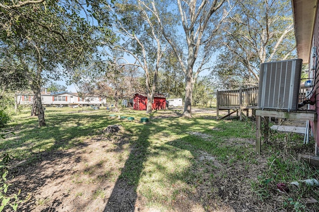 view of yard with a shed, central air condition unit, and a wooden deck