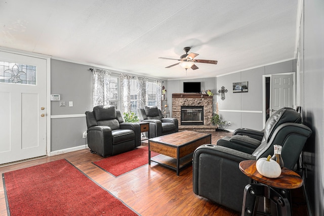 living room with ceiling fan, dark hardwood / wood-style flooring, ornamental molding, and a fireplace